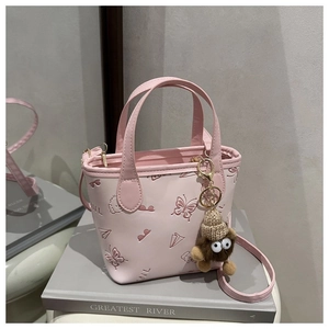 Detail view of pink bucket bag with embossed patterns and brown plush pendant charm