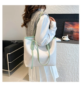 Detail of white embossed leather tote bag with green handles and heart pattern texture