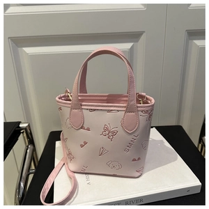 Detail of light pink mini handbag featuring embossed butterfly and dog patterns on leather