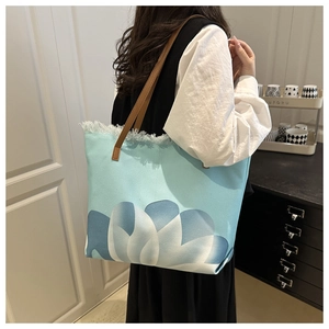 Detalle del bolso tote de lona grande con estampado floral y asas de cuero marrón