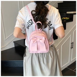 Detailed view of mini pink backpack featuring a stylish bow and smooth synthetic texture
