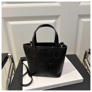 Detail of black faux leather tote featuring embossed SMNL letters and artistic motifs