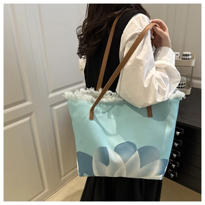 Dettaglio della borsa tote in tela azzurra con stampa floreale e bordo a frange