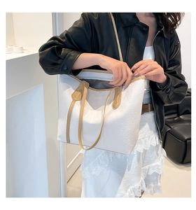 Detailed view of the embossed heart pattern and slim brown straps on a white tote bag