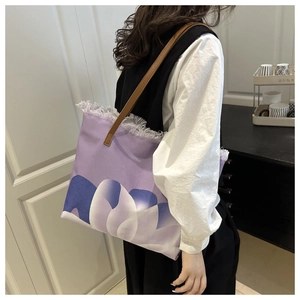 Dettaglio della borsa tote in tela viola con stampa floreale, frange e tracolla in pelle