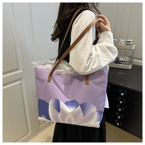Dettaglio della grande borsa tote in tela con stampe floreali viola e bordi a frange