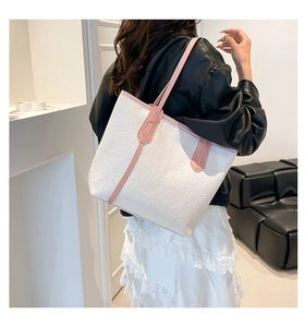 Close-up of embossed cartoon patterns and pink leather strap on a white tote bag