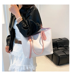Close-up of white embossed tote bag featuring cat patterns and pink contrast handles