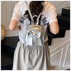 Silver mini backpack with large bow decoration shown on model back for size and style