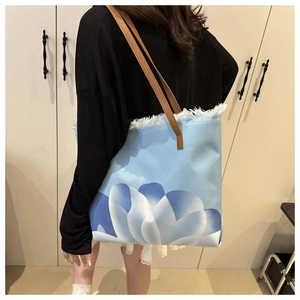 Dettaglio della borsa tote in tela floreale con frange e manici lunghi in ecopelle marrone