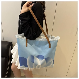 Dettaglio della borsa tote azzurra con bordi sfrangiati e manici in pelle marrone