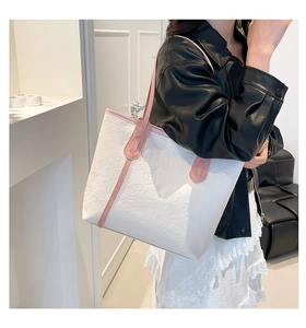 Detail of white embossed leather tote with pink trim and cartoon pattern textures