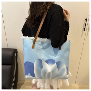 Vista detallada del bolso tote de lona con estampado floral azul y flecos blancos
