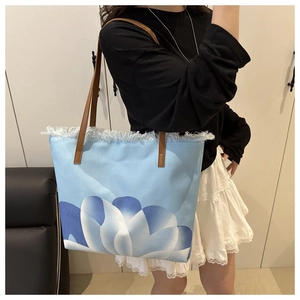Dettaglio borsa tote in tela blu con stampa floreale, bordi sfrangiati e manici