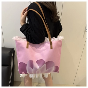 Borsa tote in tela rosa con dettagli in nappe e stampe floreali viola sulla spalla
