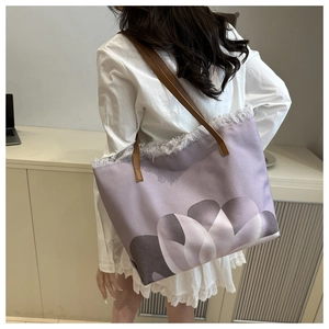 Dettaglio della borsa tote in tela viola con frange e manici in pelle marrone