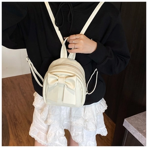 Detail of a creamy white mini backpack featuring a large bow and premium PU leather texture