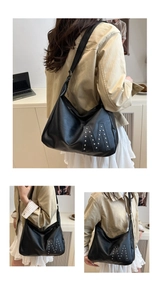 Details einer großen schwarzen Hobo-Umhängetasche mit Nieten-M-Design für Damen