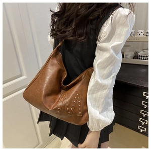 Detail einer braunen Hobo-Tasche aus Vintage-Leder mit silberner M-Niete am Modell