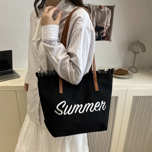 Black canvas tote bag with brown leather handles, fringe trim, and Summer embroidery