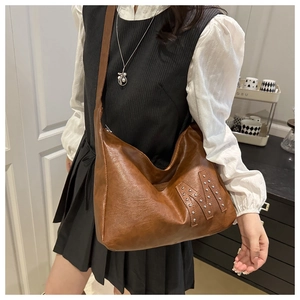 Braune Hobo-Schultertasche aus Leder mit dekorativem M-Muster aus silbernen Nieten