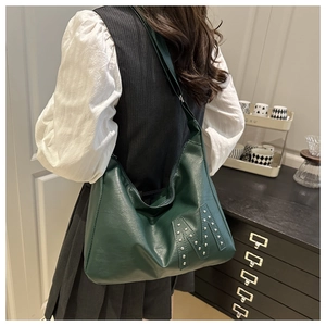 Detailansicht der großen dunkelgrünen Hobo-Tasche aus PU-Leder mit M-Nietendesign an Model