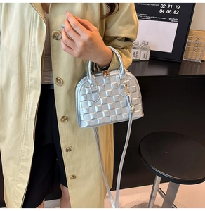 Detail of silver shell bag with checkered embossing and elegant metal finish worn by model