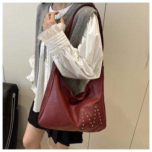 Details der burgunderroten PU-Ledertasche mit silbernem M-Nietmuster am Modell