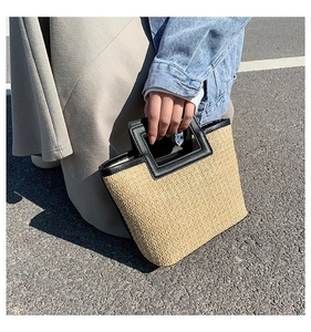 Vue détaillée du sac en paille tissée avec finitions et anses en cuir noir