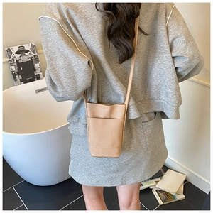 Mini brown bucket bag with lychee texture shown in a lifestyle indoor setting