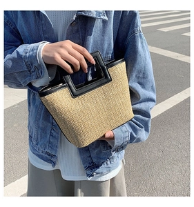 Détail du sac cabas en paille tressée avec poignées et bordures en cuir noir