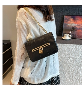 Detailed view of black crocodile pattern bag with gold padlock and chain strap
