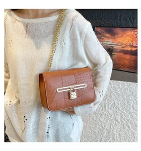 Detail of crocodile pattern shoulder bag with a gold padlock charm and chain strap
