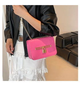 Detail of bright pink crocodile pattern texture and gold chain on small square bag