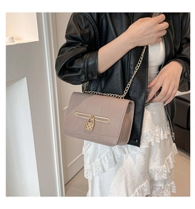 Detail of lavender faux leather shoulder bag with crocodile pattern and golden lock