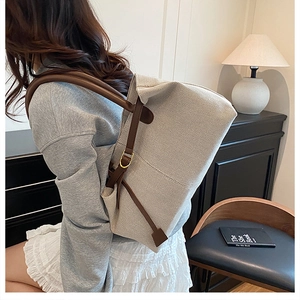 Detail of beige canvas tote bag with adjustable brown leather straps and metal buckle