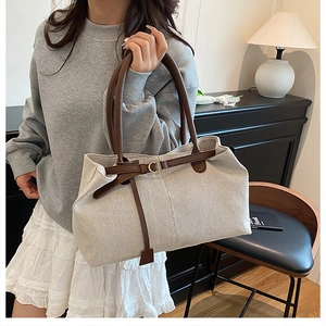 Close-up of beige woven fabric texture and brown leather strap on a vintage tote bag