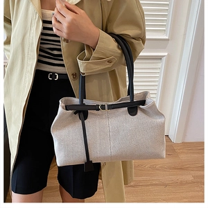 Close-up of canvas tote bag featuring leather handles and metal buckle detail