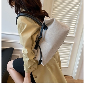 Close-up of beige canvas tote bag with black leather straps and gold metal hardware