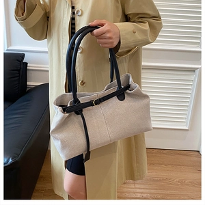 Detail of off-white canvas tote with black leather handles and gold buckle accent