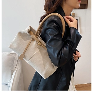 Side view of linen tote bag with khaki leather handles and metal buckle detail on model