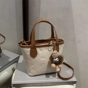 Chic cream and brown tote bag with embossed patterns and plush monster charm on books