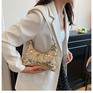 Close-up of golden sequin hobo bag worn by a model in a stylish white blazer outfit