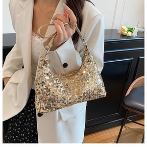 Close-up of a gold sequin crescent shoulder bag styled with a white blazer for a chic look