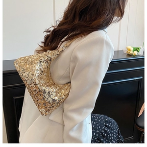 Close-up of gold sequin shoulder bag on model wearing white blazer and floral dress