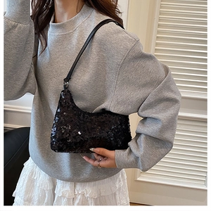 Detail of stylish black sequin hobo bag worn by model over a grey sweatshirt