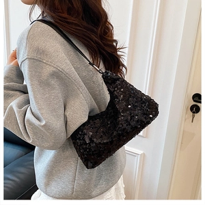 Close-up of black sequined shoulder bag showing reflective texture and adjustable strap