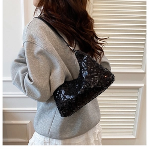 Detail of a chic black sequin shoulder bag worn by a model in casual grey hoodie