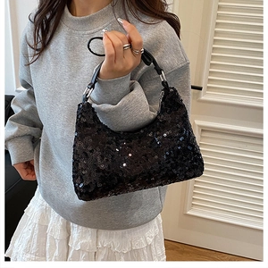 Close-up of black sequin hobo bag with silver metal ring and leather shoulder strap
