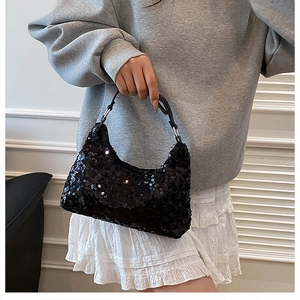 Model wearing a black sequined underarm bag with silver hardware and glossy finish